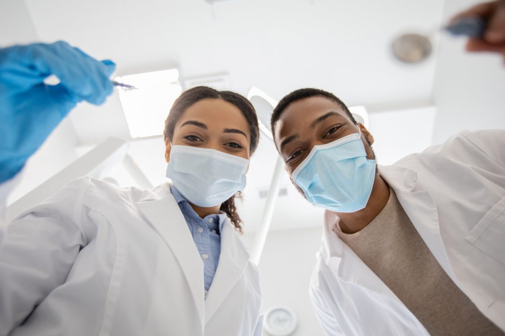 Black Dentist Doctor And His Female Assistant Examinating Patients Teeth, Low Angle
